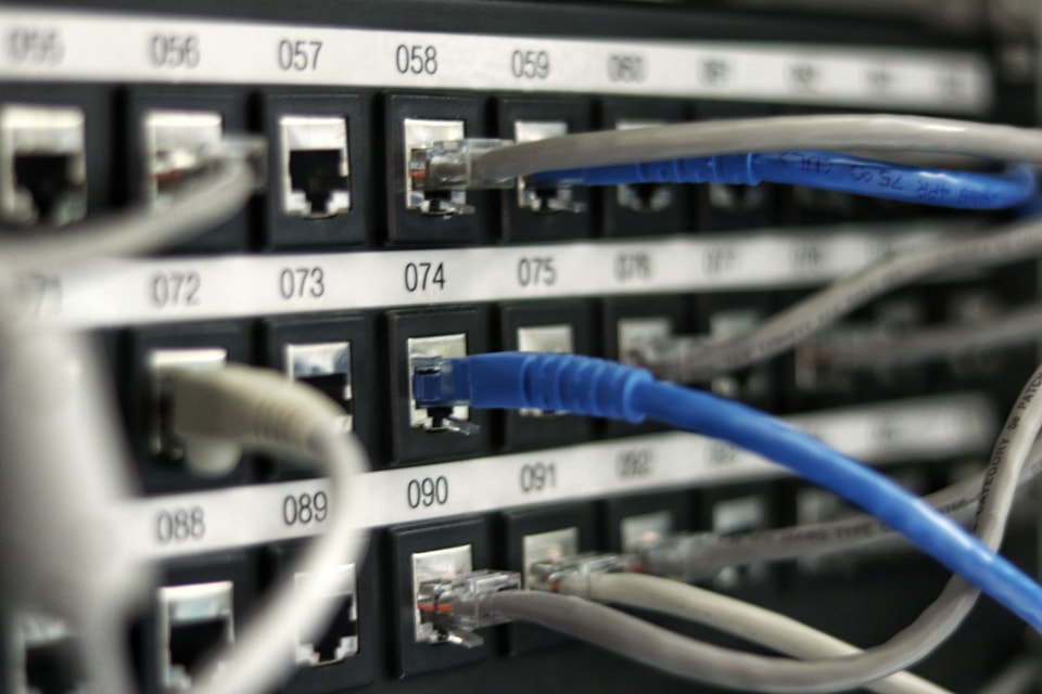 Technician reviewing cabling and network equipment in a commercial server environment.